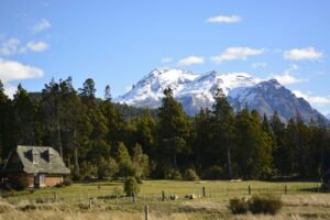 Scenic view of a house amidst trees with a snow-capped mountain in Esquel, Argentina.