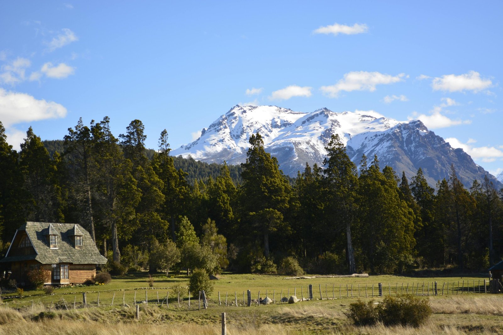 Scenic view of a house amidst trees with a snow-capped mountain in Esquel, Argentina.