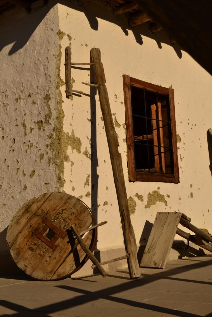 Sunlit exterior of an abandoned building with rustic wooden details and a window.