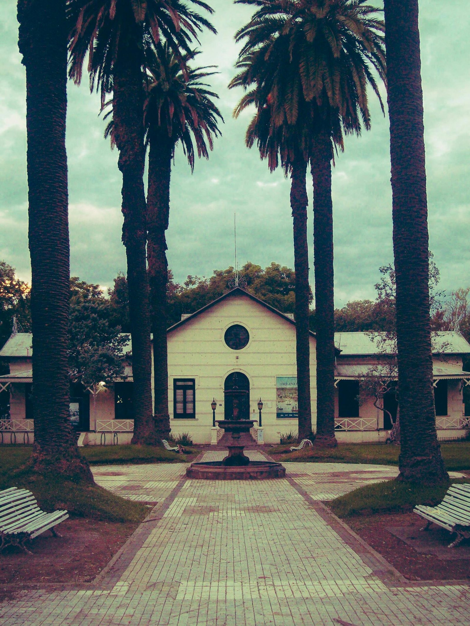 Charming historic building with palm trees in a tranquil park setting in Rosario, Argentina.